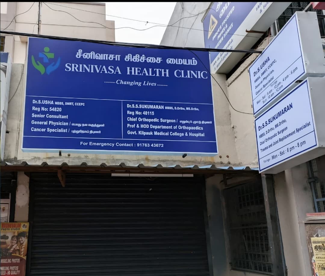 Signboard of Srinivasa Health Clinic (சீனிவாசா சிகிச்சை மையம்) on Rangarajapuram Main Road, Kodambakkam, listing Dr. S. Usha, General Physician and Cancer Specialist, and Dr. S.S. Sukumaran, Chief Orthopedic Surgeon